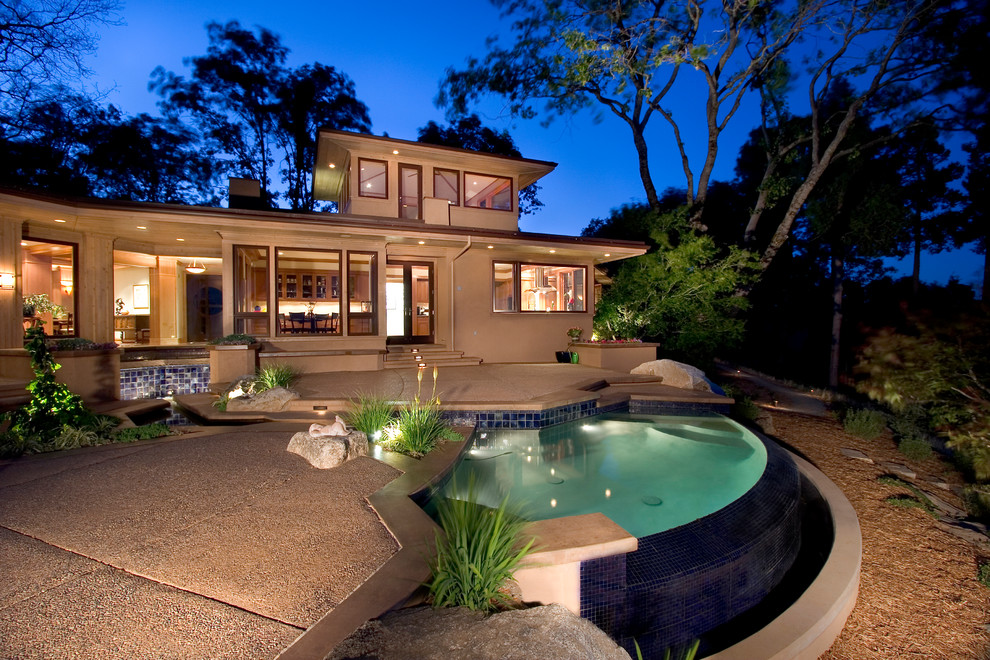 Идея дизайна: бассейн-инфинити среднего размера, произвольной формы на заднем дворе в современном стиле с джакузи и покрытием из бетонных плит