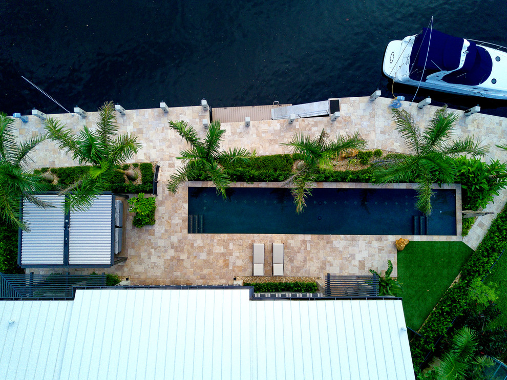 Immagine di una piscina monocorsia moderna rettangolare di medie dimensioni e dietro casa con una dépendance a bordo piscina e pavimentazioni in pietra naturale