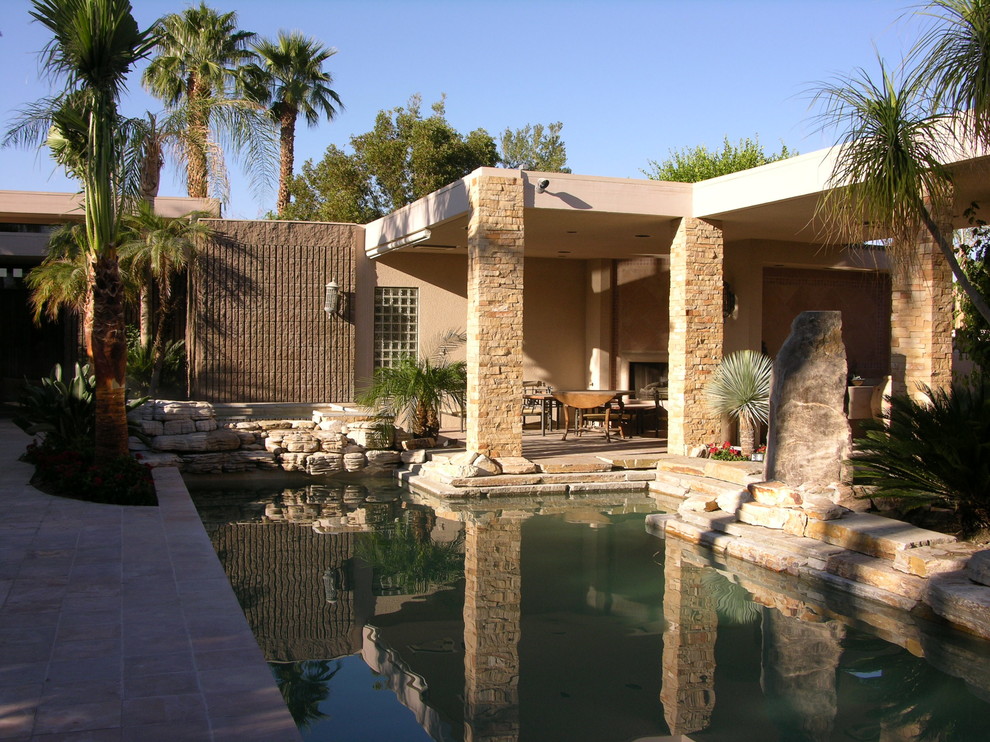 Стильный дизайн: большой естественный, угловой бассейн на внутреннем дворе в средиземноморском стиле с домиком у бассейна и покрытием из каменной брусчатки - последний тренд