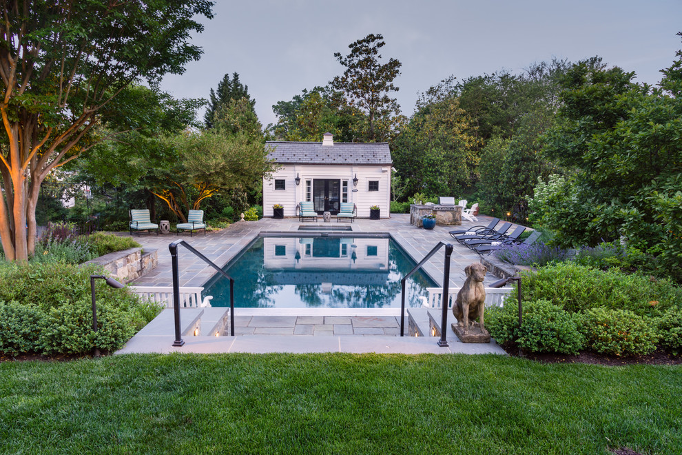 Photo of a large traditional back rectangular lengths swimming pool in DC Metro with a pool house and natural stone paving.