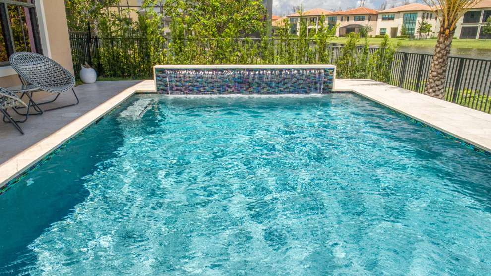 Idee per una piscina monocorsia tropicale rettangolare di medie dimensioni e dietro casa con una vasca idromassaggio e pavimentazioni in pietra naturale