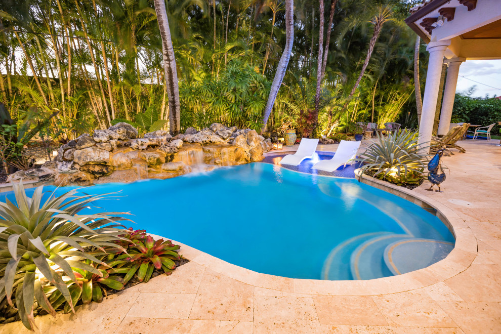 Imagen de piscina alargada exótica grande a medida en patio trasero con suelo de baldosas