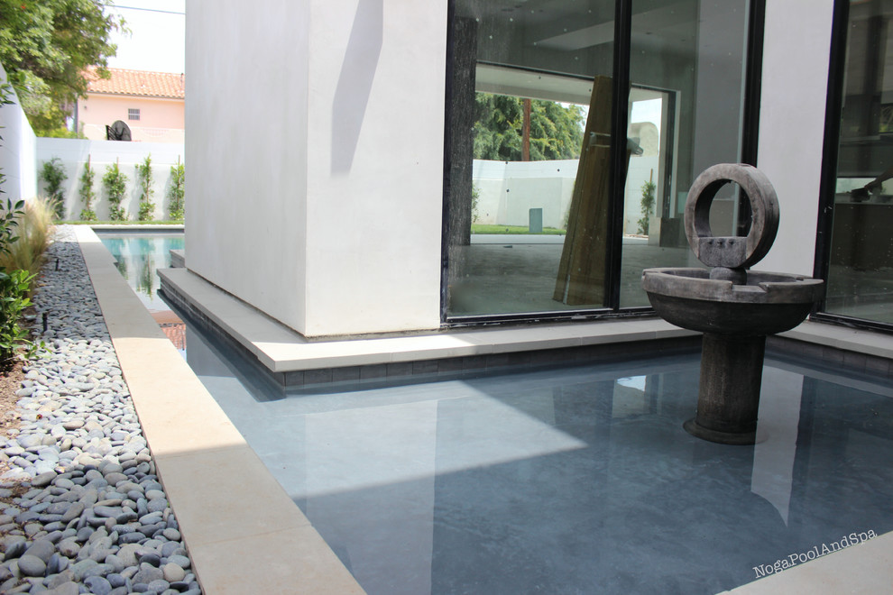 Foto de piscinas y jacuzzis alargados minimalistas de tamaño medio a medida en patio trasero con suelo de hormigón estampado