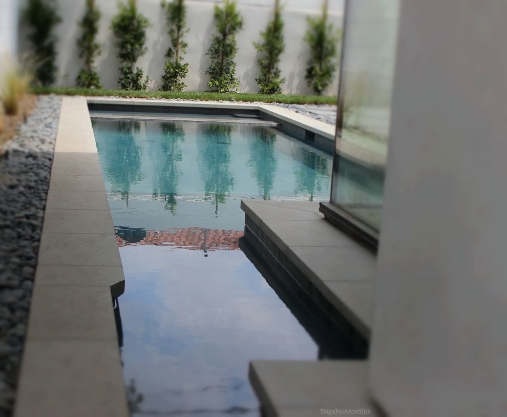 Modelo de piscinas y jacuzzis alargados minimalistas de tamaño medio a medida en patio trasero con suelo de hormigón estampado