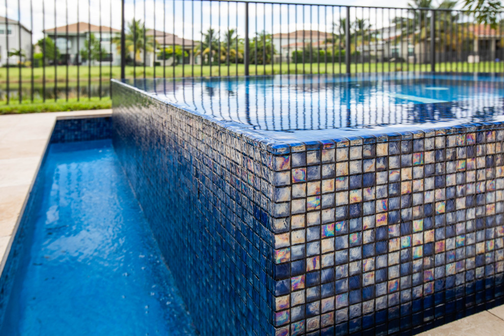 Ispirazione per una piscina minimalista rettangolare di medie dimensioni e dietro casa con una vasca idromassaggio e pavimentazioni in pietra naturale