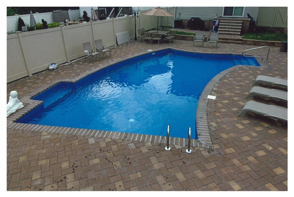 Imagen de piscina alargada clásica grande tipo riñón en patio trasero con adoquines de ladrillo