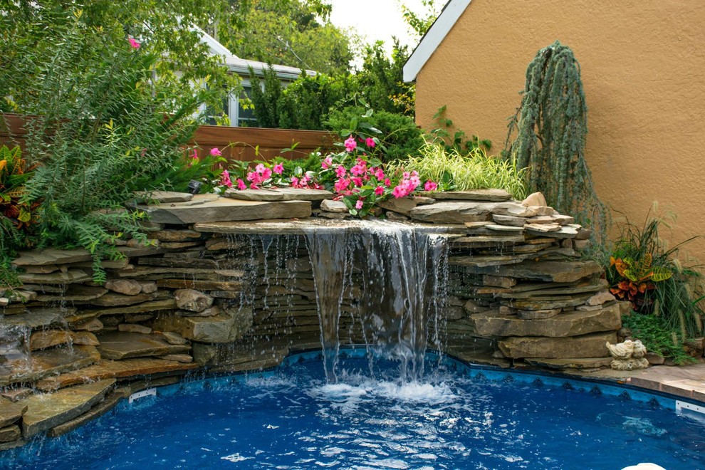 Foto de piscinas y jacuzzis alargados actuales grandes a medida en patio trasero con adoquines de piedra natural