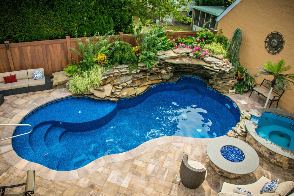 Modelo de piscinas y jacuzzis alargados actuales grandes a medida en patio trasero con adoquines de piedra natural