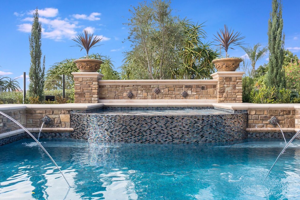 Immagine di una grande piscina design personalizzata dietro casa con pavimentazioni in pietra naturale