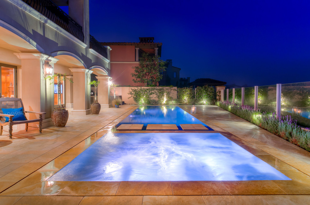 На фото: прямоугольный бассейн-инфинити среднего размера на заднем дворе в современном стиле с покрытием из каменной брусчатки