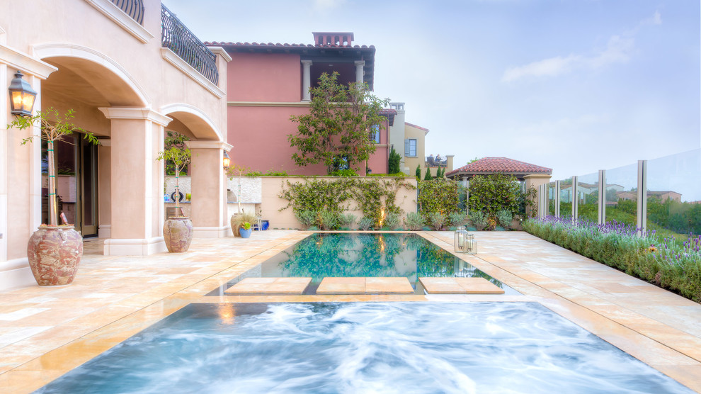 Modelo de piscina infinita contemporánea de tamaño medio rectangular en patio trasero con adoquines de piedra natural