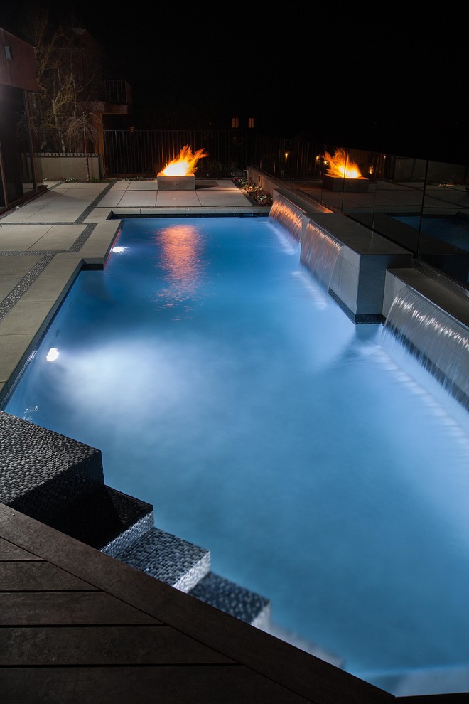 Foto de piscina con fuente contemporánea grande a medida en patio trasero con losas de hormigón