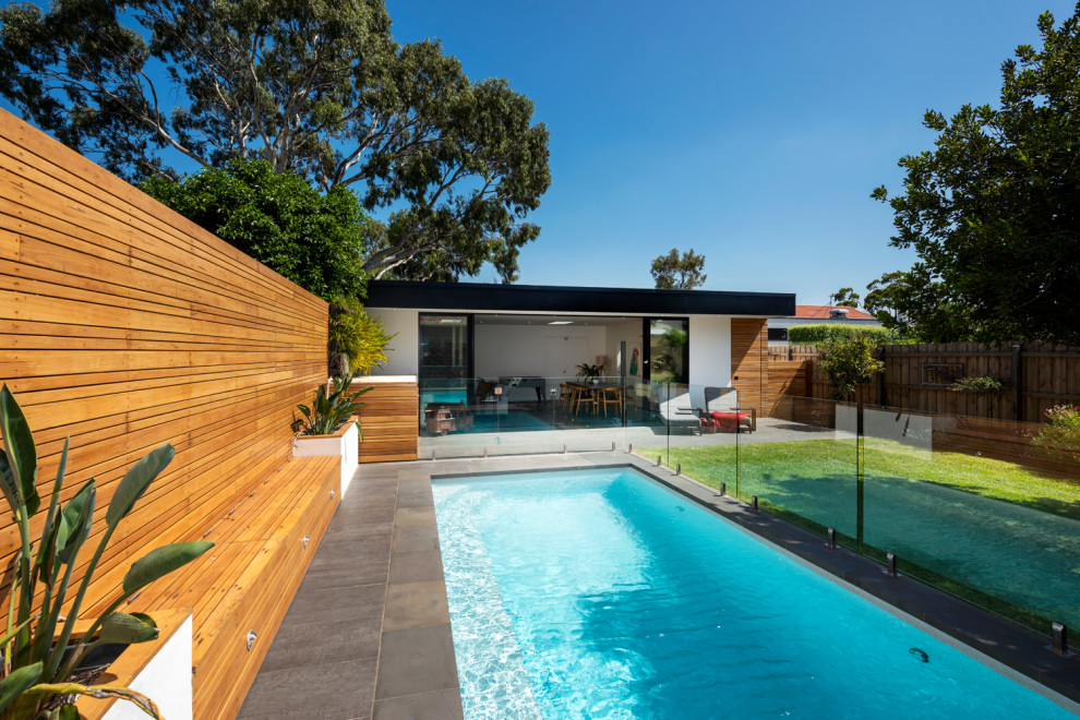 Diseño de casa de la piscina y piscina alargada contemporánea de tamaño medio rectangular en patio trasero con adoquines de piedra natural