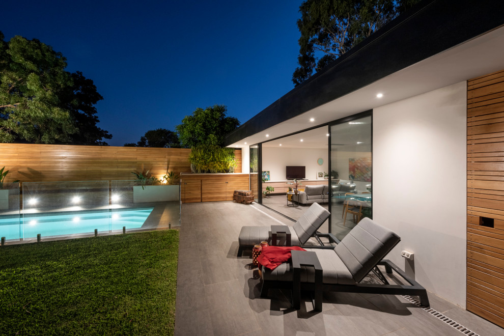 Esempio di una piscina monocorsia contemporanea rettangolare di medie dimensioni e dietro casa con una dépendance a bordo piscina e pavimentazioni in pietra naturale