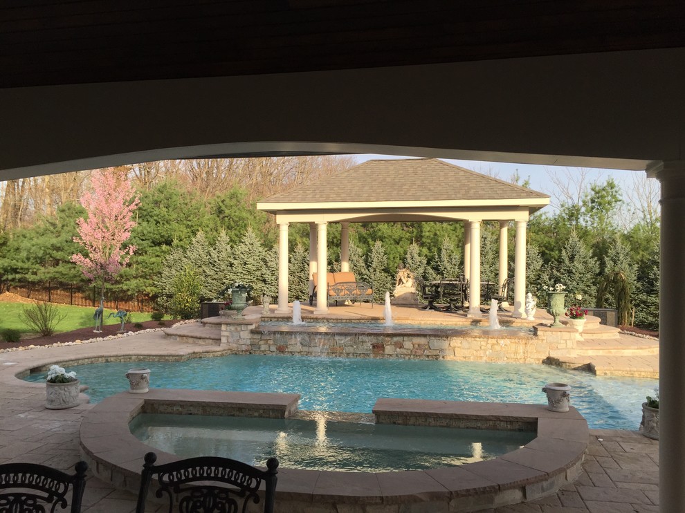 На фото: большой бассейн произвольной формы в доме в классическом стиле с фонтаном и мощением тротуарной плиткой с