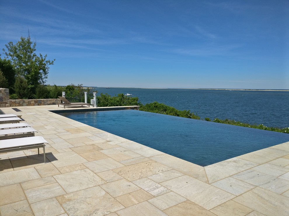Modelo de casa de la piscina y piscina marinera rectangular en patio trasero con adoquines de piedra natural