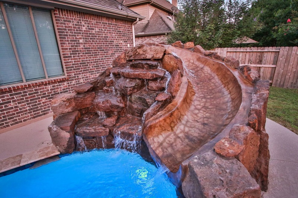 Foto de piscina con tobogán contemporánea grande a medida en patio trasero con adoquines de hormigón
