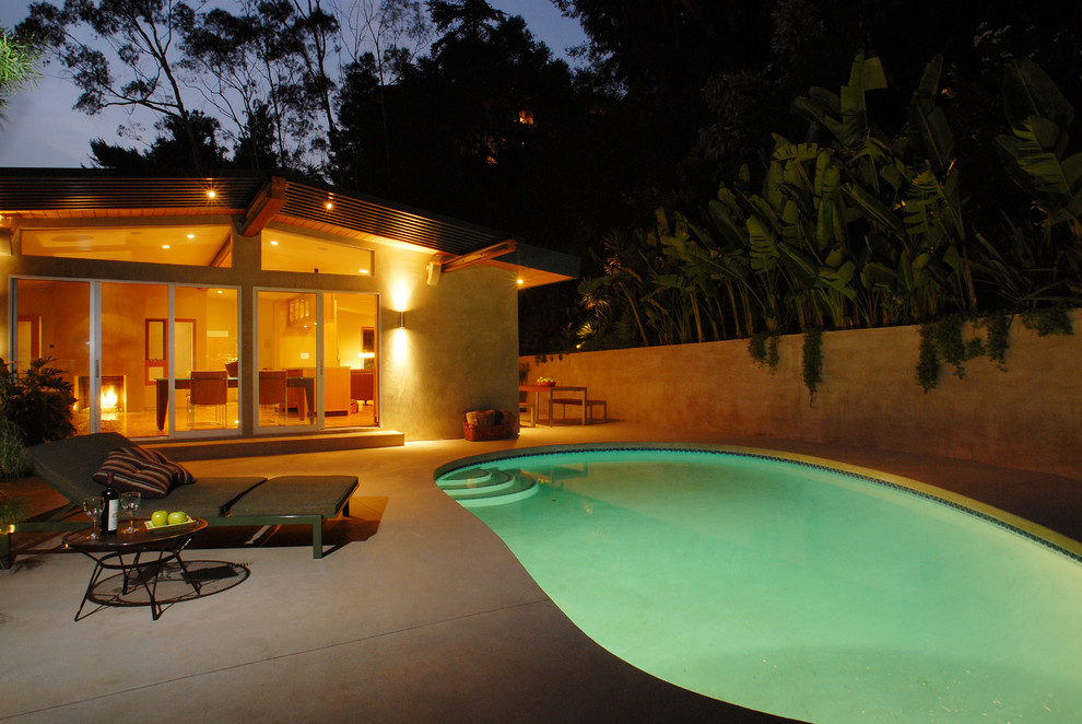 Стильный дизайн: бассейн среднего размера, в форме фасоли на боковом дворе в современном стиле с покрытием из бетонных плит - последний тренд
