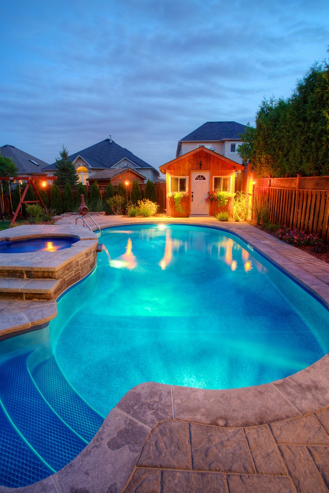 Foto de casa de la piscina y piscina natural tradicional de tamaño medio a medida en patio trasero con adoquines de piedra natural