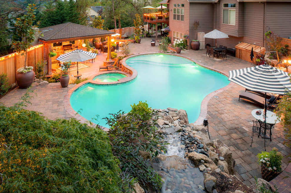 Large tuscan backyard brick and kidney-shaped pool photo in Portland