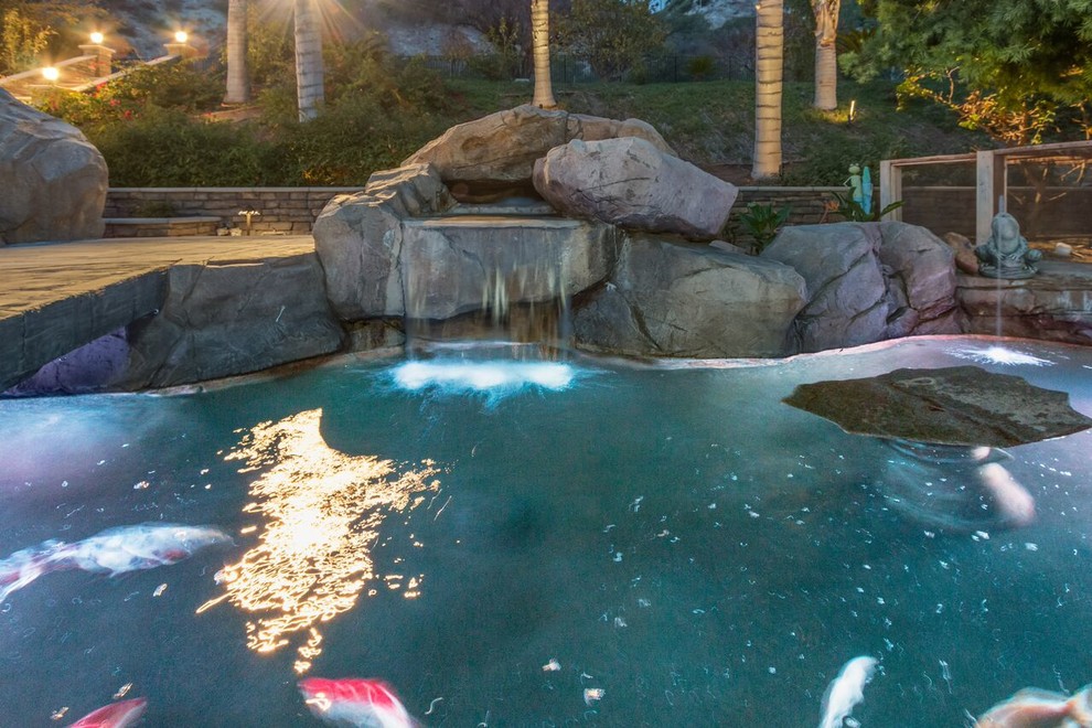 Ejemplo de piscina con tobogán contemporánea grande a medida en patio trasero con adoquines de hormigón