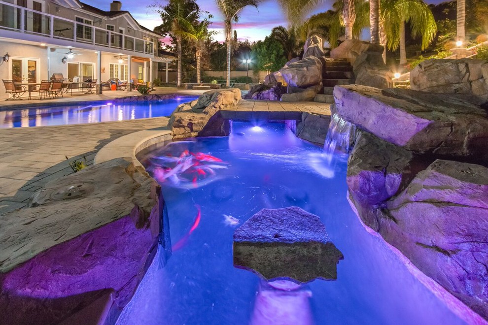 Immagine di una grande piscina chic personalizzata dietro casa con un acquascivolo e pavimentazioni in cemento