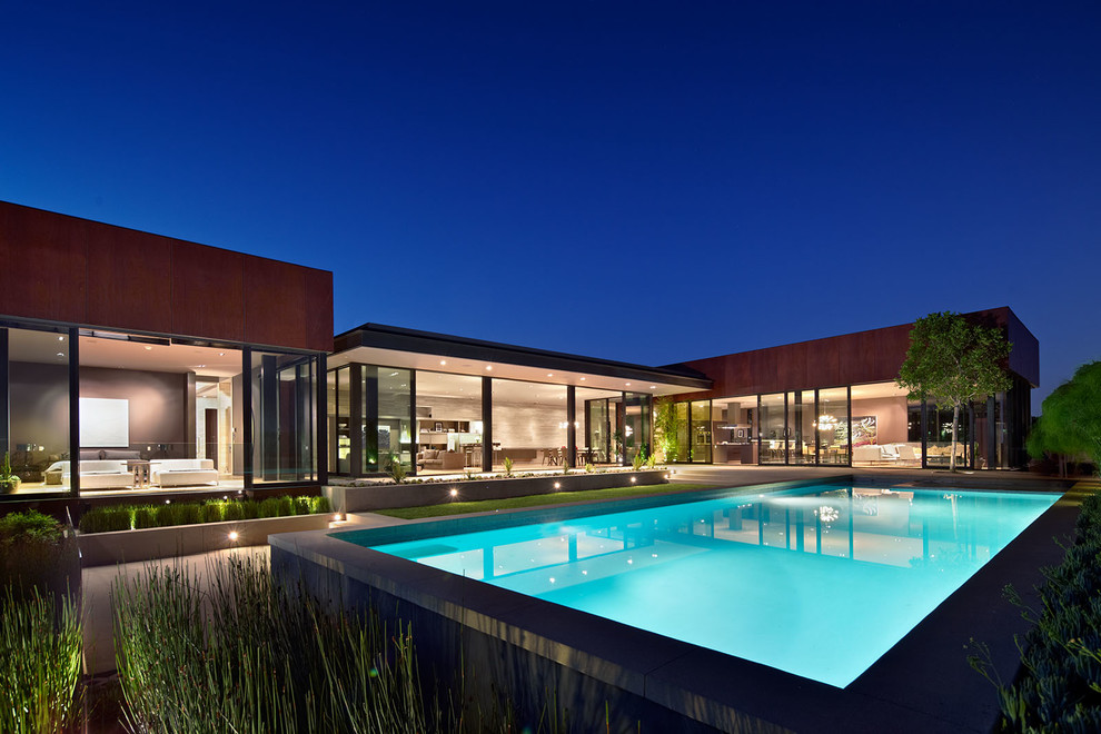Expansive contemporary back rectangular above ground swimming pool in Los Angeles with a pool house and concrete slabs.