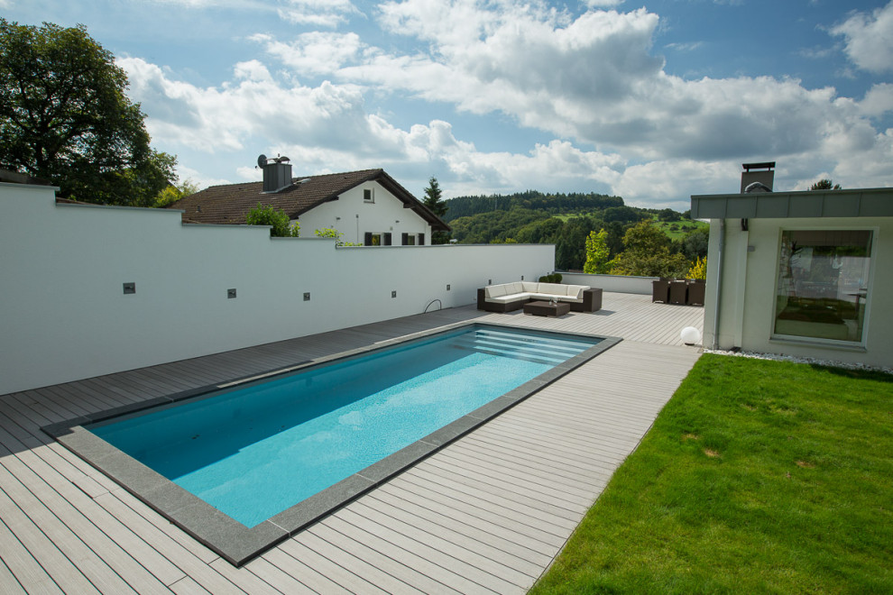 Inspiration för stora moderna rektangulär pooler längs med huset, med trädäck
