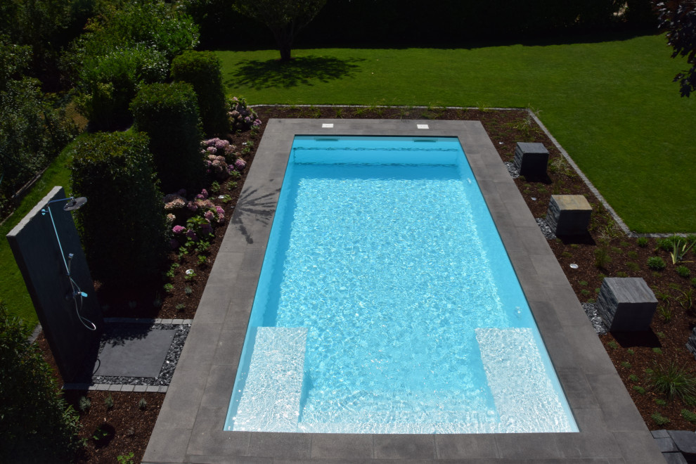 Ejemplo de piscina contemporánea de tamaño medio rectangular en patio lateral con adoquines de piedra natural