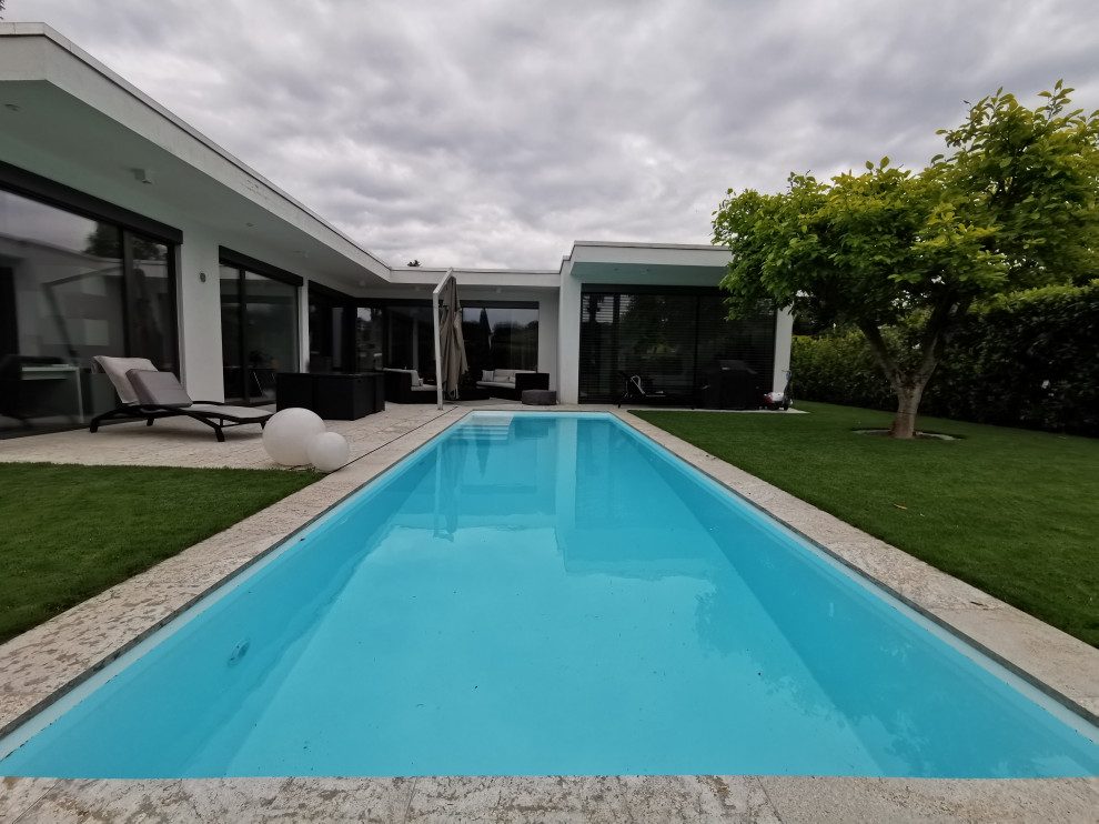 Inspiration pour un grand piscine avec aménagement paysager latéral design rectangle avec des pavés en pierre naturelle.