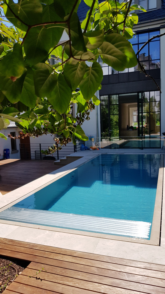Ejemplo de piscina infinita contemporánea de tamaño medio rectangular en patio trasero con adoquines de piedra natural