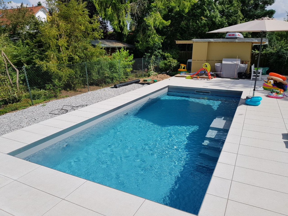 Ejemplo de piscina actual de tamaño medio rectangular en patio lateral con adoquines de piedra natural