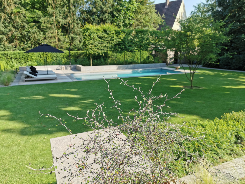 Foto på en stor funkis pool längs med huset, med naturstensplattor