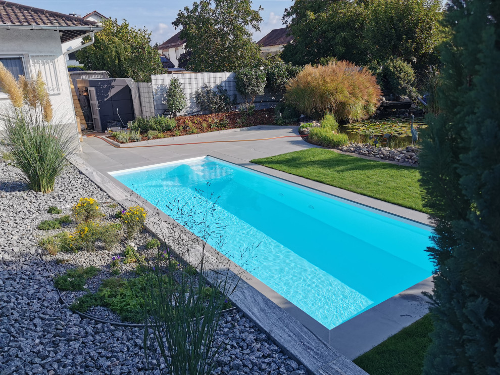 Modelo de piscina actual de tamaño medio rectangular en patio lateral con suelo de baldosas