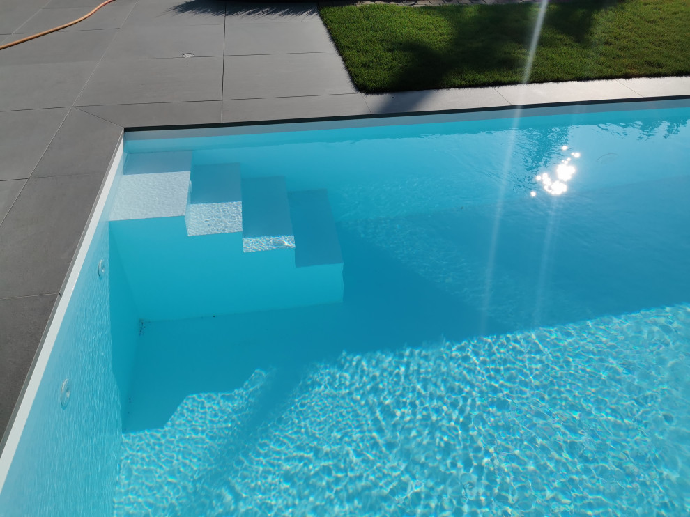 На фото: прямоугольный бассейн среднего размера на боковом дворе в современном стиле с покрытием из плитки