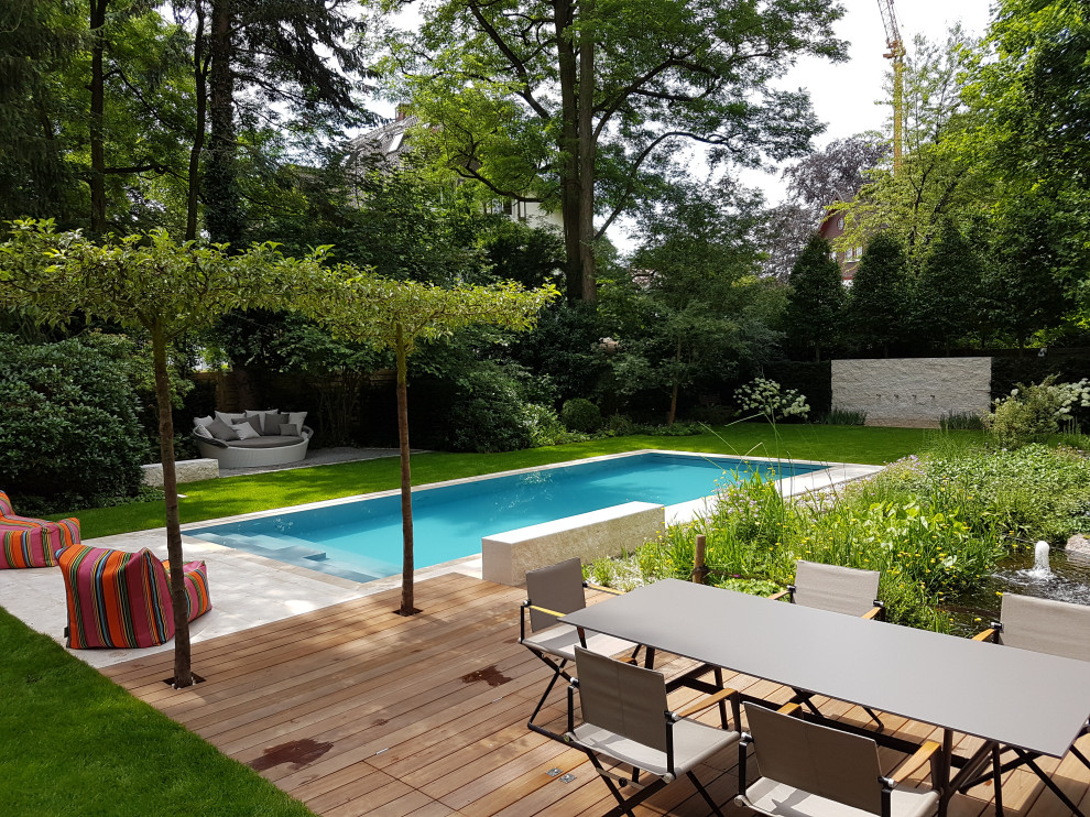 Imagen de piscina con tobogán actual grande rectangular en patio lateral con adoquines de piedra natural