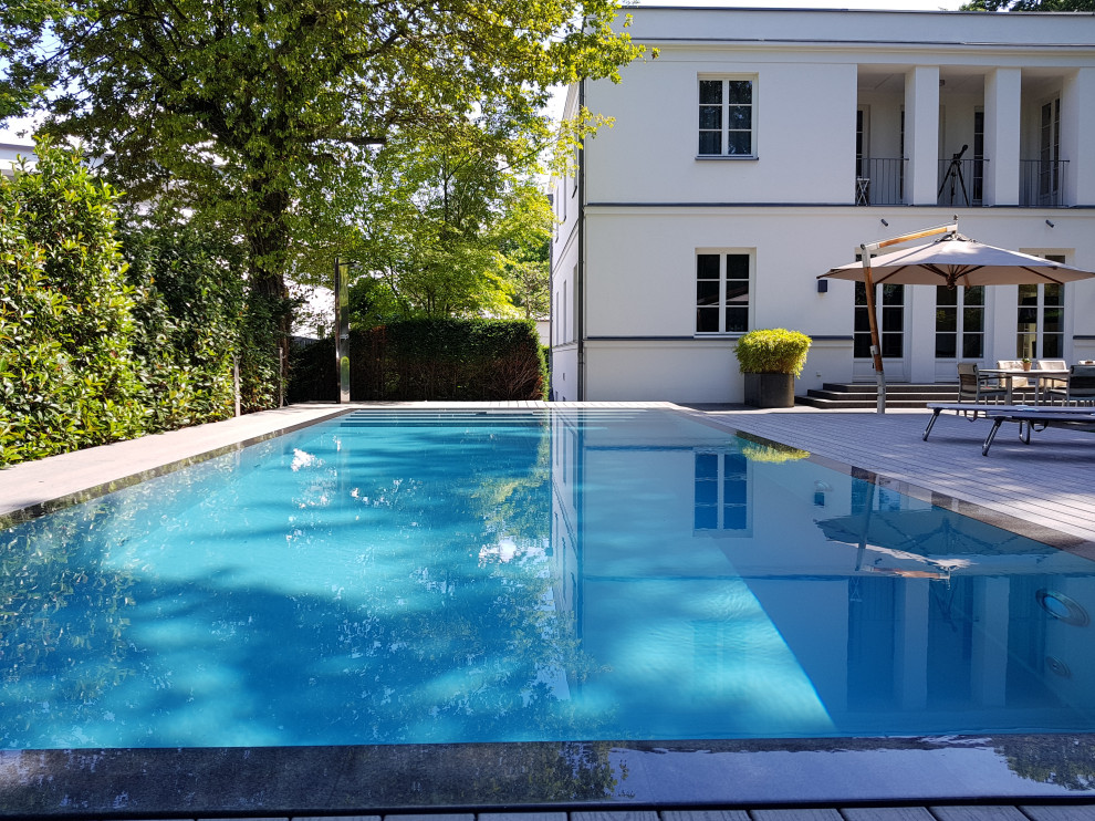 Ejemplo de piscina actual grande rectangular en patio lateral con entablado