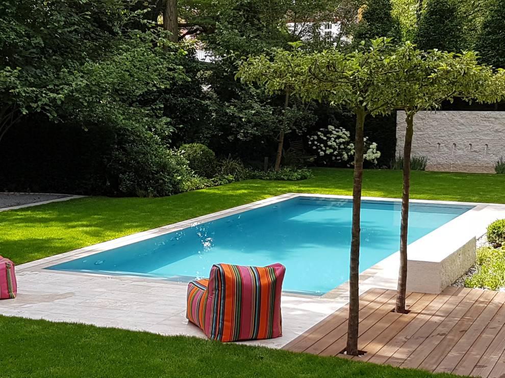 Cette image montre une grande piscine latérale design rectangle avec un toboggan et des pavés en pierre naturelle.