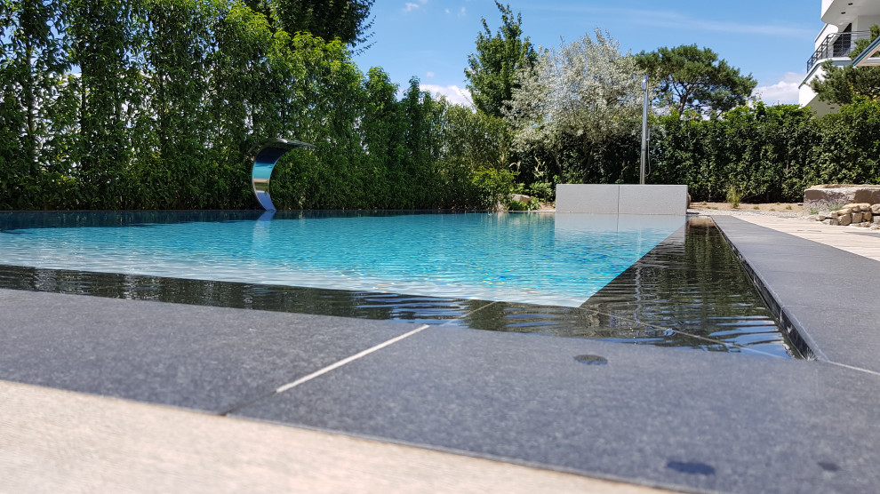 Foto de piscina infinita mediterránea grande rectangular en patio lateral con adoquines de piedra natural