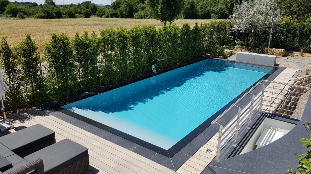 Großer Mediterraner Infinity-Pool neben dem Haus in rechteckiger Form mit Natursteinplatten in Frankfurt am Main
