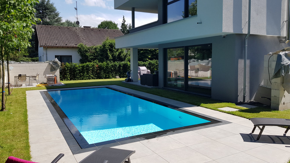 Ejemplo de piscina infinita contemporánea grande rectangular en patio lateral con adoquines de piedra natural
