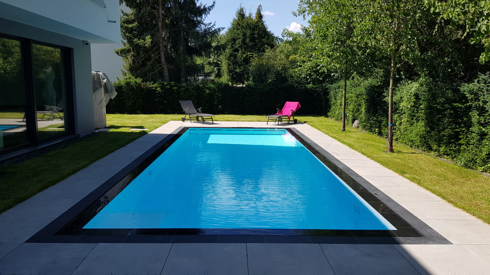 Свежая идея для дизайна: большой прямоугольный бассейн-инфинити на боковом дворе в современном стиле с покрытием из каменной брусчатки - отличное фото интерьера
