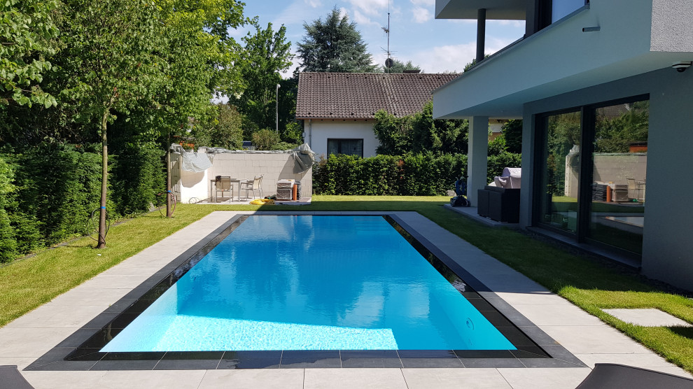 Großer Moderner Infinity-Pool neben dem Haus in rechteckiger Form mit Natursteinplatten in Frankfurt am Main