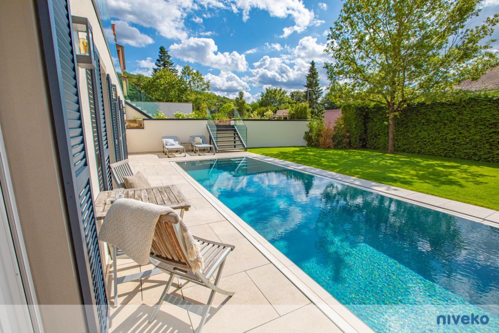 Ejemplo de piscina infinita de estilo de casa de campo grande rectangular en patio delantero con adoquines de piedra natural