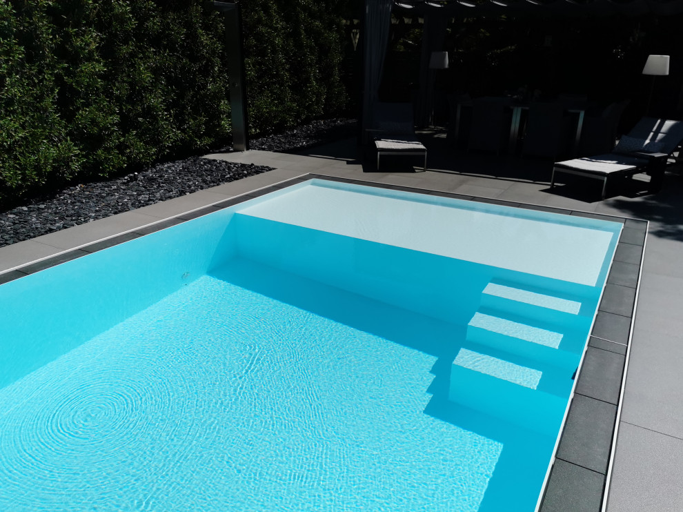 На фото: большой прямоугольный бассейн-инфинити на боковом дворе в современном стиле с покрытием из плитки