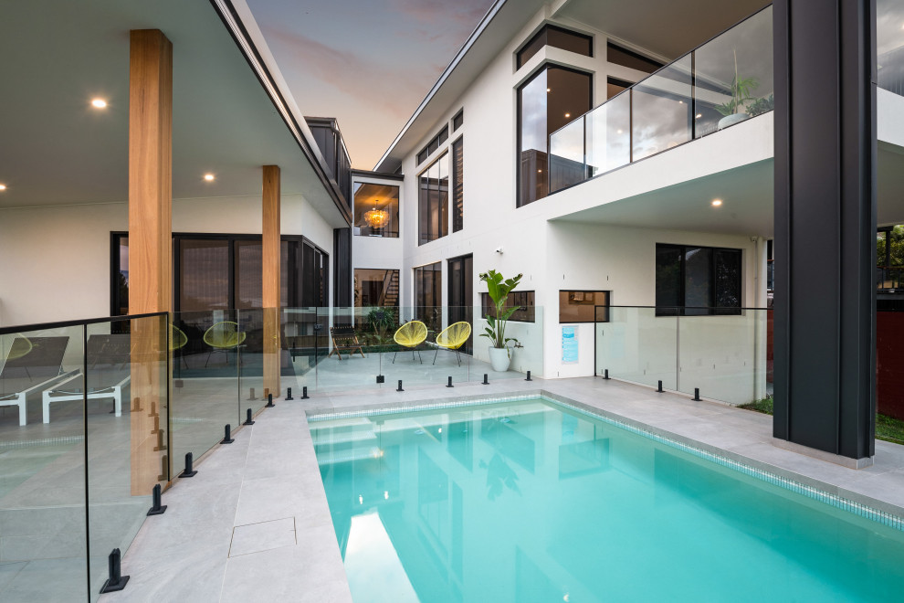 Immagine di una grande piscina monocorsia design rettangolare dietro casa con piastrelle