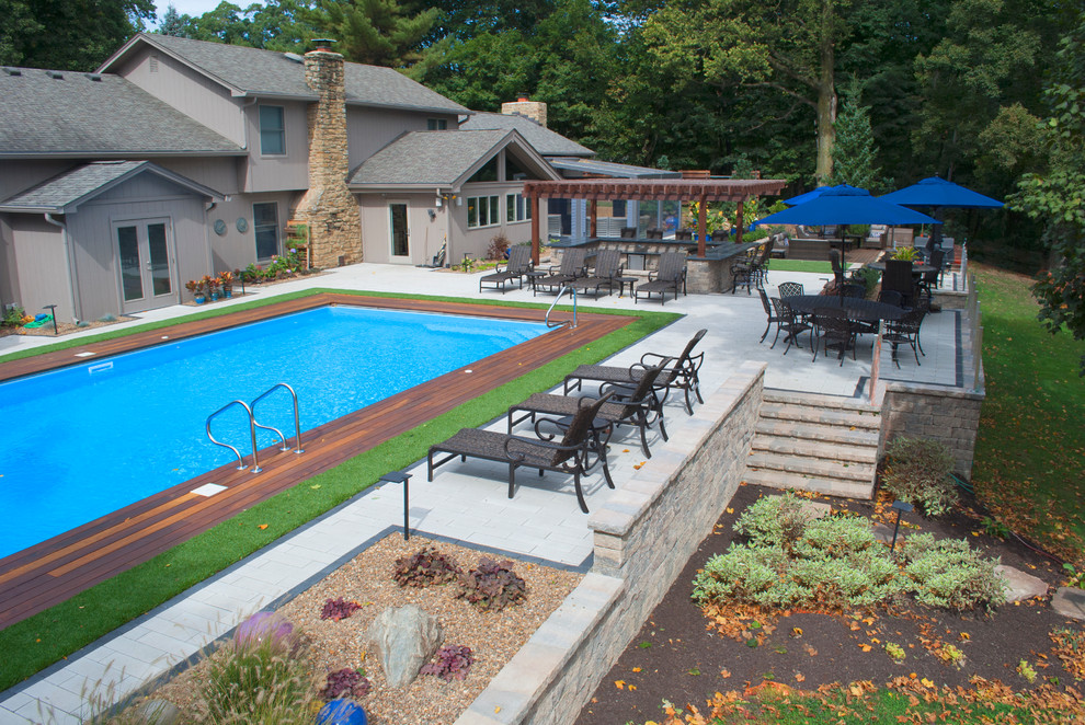Modelo de piscina contemporánea grande en patio trasero con adoquines de hormigón