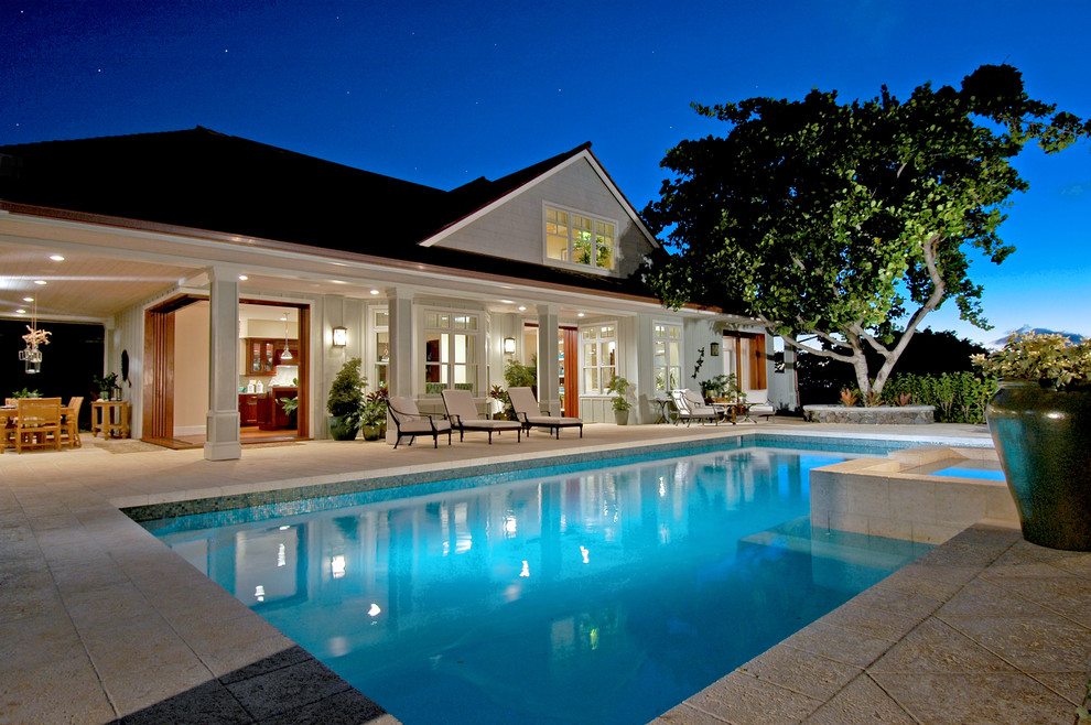 Esempio di una grande piscina tropicale rettangolare dietro casa con una vasca idromassaggio e pavimentazioni in cemento