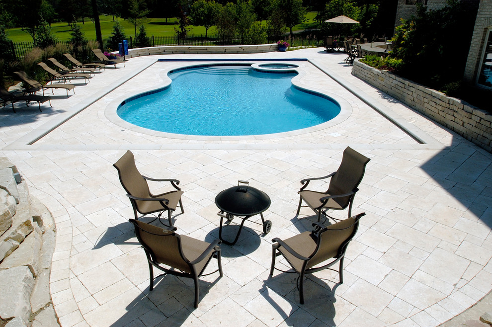 Immagine di un'ampia piscina naturale tradizionale personalizzata dietro casa con una vasca idromassaggio e pavimentazioni in pietra naturale