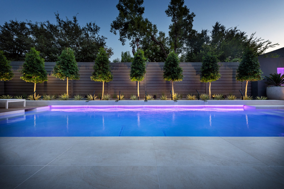 Diseño de piscina minimalista grande rectangular en patio trasero con paisajismo de piscina y adoquines de piedra natural